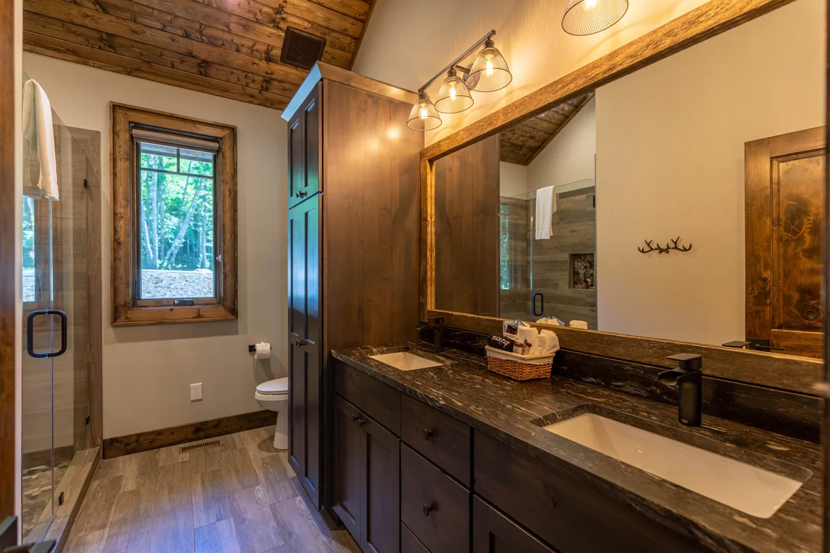 A serene bathroom featuring a double vanity with a large mirror, wooden accents, and a modern shower area. The space feels bright, clean, and designed for comfort and refreshment.
