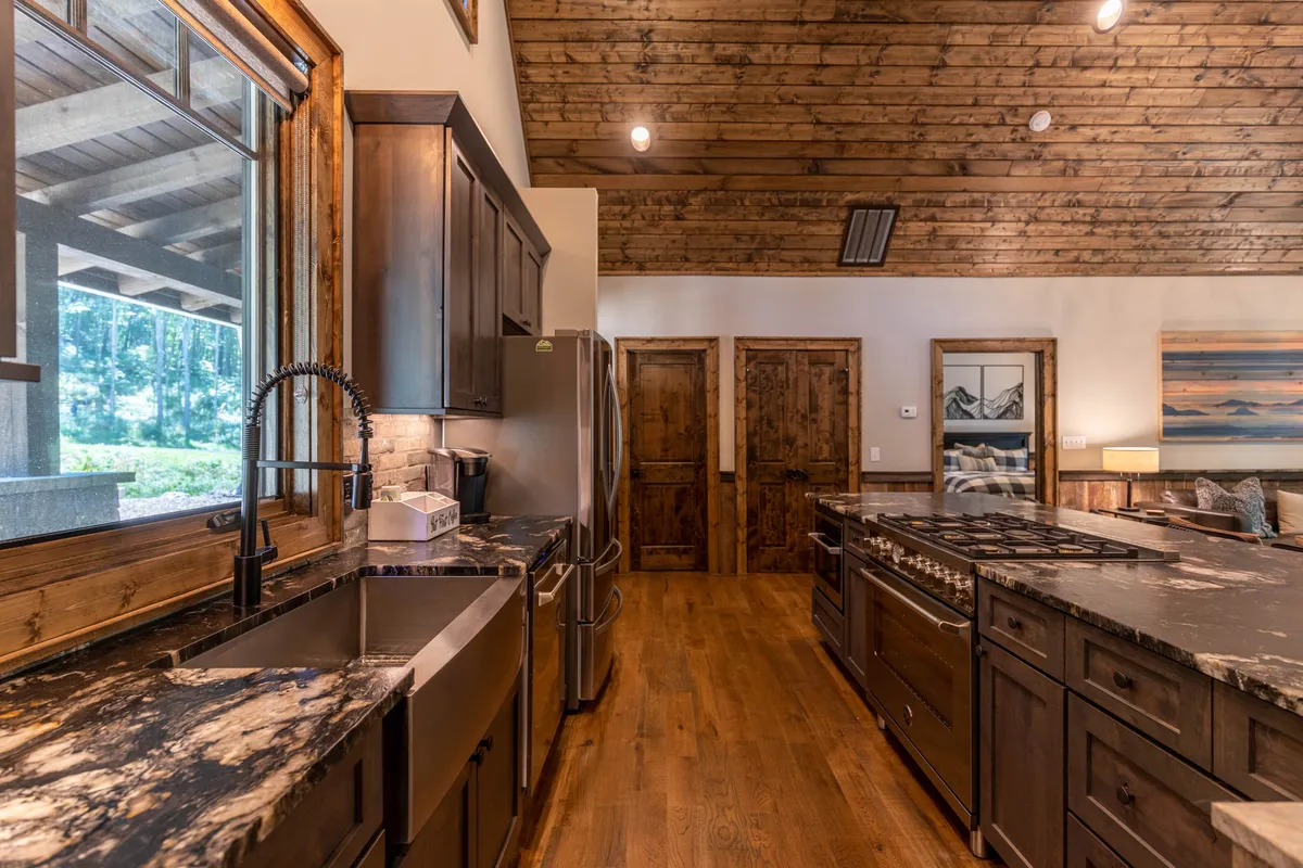 A warm and inviting kitchen highlighted by a spacious island, granite countertops, stainless steel appliances, and large windows that flood the area with natural light. The scene emphasizes the room's readiness for cooking, entertaining, and family gatherings.